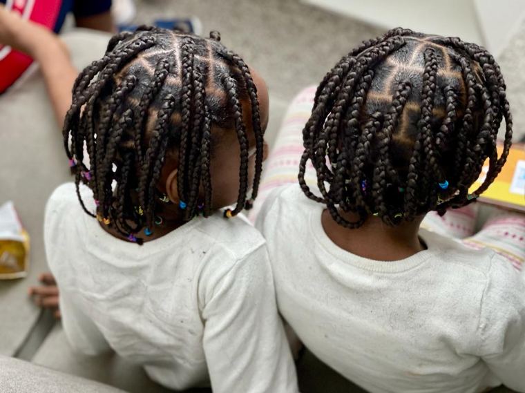 Two children with beaded box braids, back view